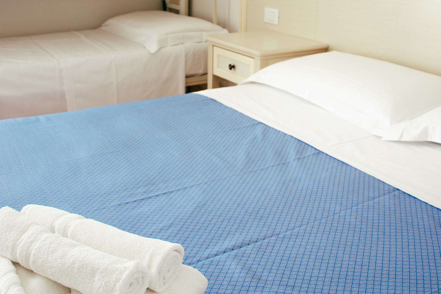 Dettaglio delle lenzuola azzurre e bianche del letto matrimoniale della camera family economy dell'Hotel Principe Caorle