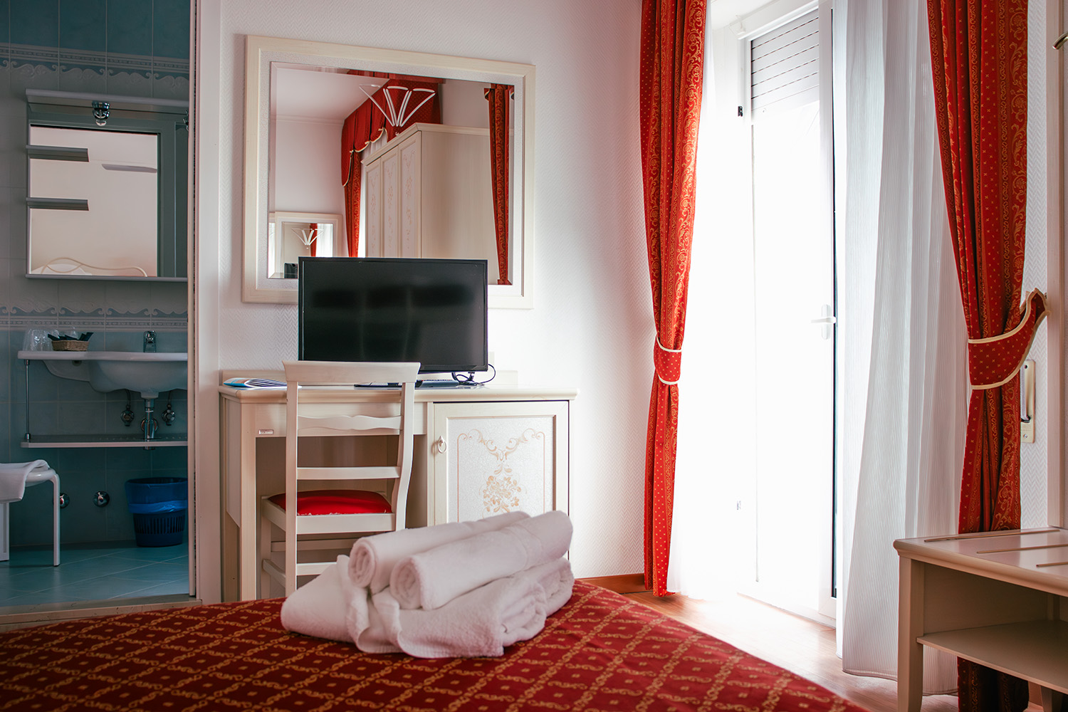 la camera family dell'Hotel Principe Caorle con lenzuola e tende rosse